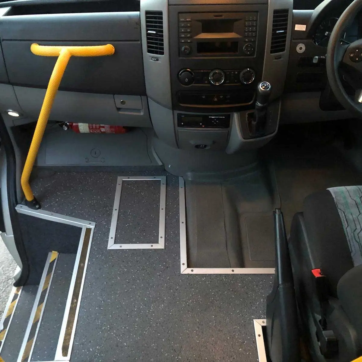 Drivers seat of van with railing to help passengers on and off the bus